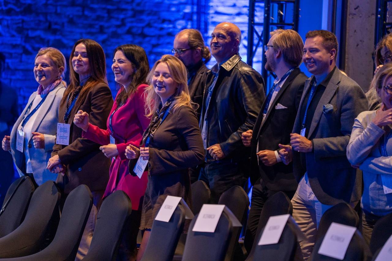 The audience on its feet, arms linked, at Pete Ward's keynote for ALAB in Żnin, Poland, May 2026